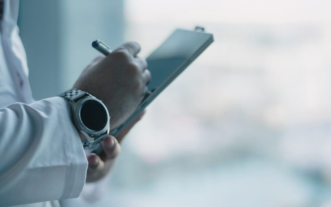 Doctor writing on clipboard wearing smartwatch